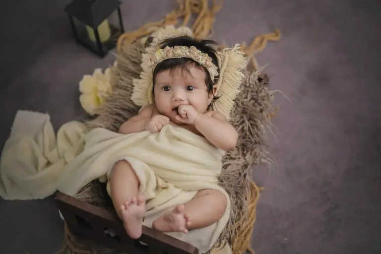 Newborn baby wrapped in a cream blanket in a basket with a flower headband